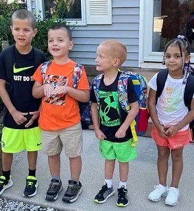 Four children with backpacks heading off to school